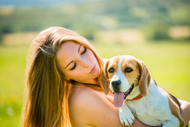 Teen girl holding her pet (beagle dog) - outdoor in nature - Fotó, kép