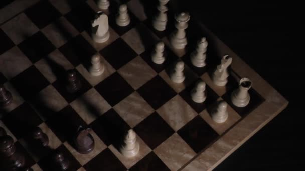 Sombras de ajedrez en la oscuridad. Tablero de ajedrez con piezas. Sombra de piezas de ajedrez sobre un fondo oscuro. Sombras de ajedrez en un tablero de ajedrez. La luz ilumina piezas de ajedrez
. - Metraje, vídeo