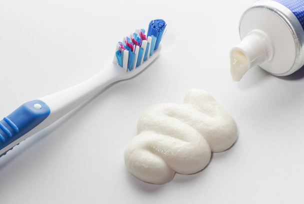 Cepillo de dientes y pasta de dientes exprimida sobre fondo blanco, concepto de cuidado oral
. - Foto, Imagen