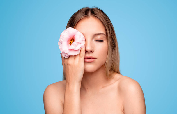 Beautiful female model with flower near eye - Фото, изображение