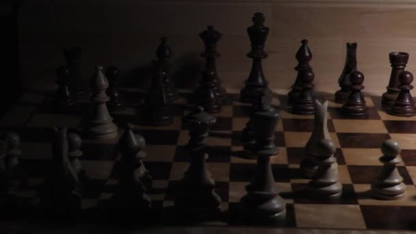 A sakk árnyékai a sötétben. Sakktábla darabokkal. Sakkfigurák árnyéka sötét háttérrel. Sakk árnyékok a sakktáblán. A fény megvilágítja a sakkfigurákat. - Felvétel, videó