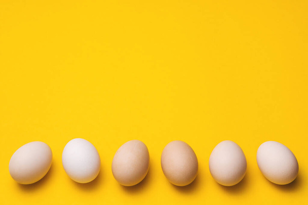 natural ecological eggs on yellow background in a row with copyspace - Valokuva, kuva