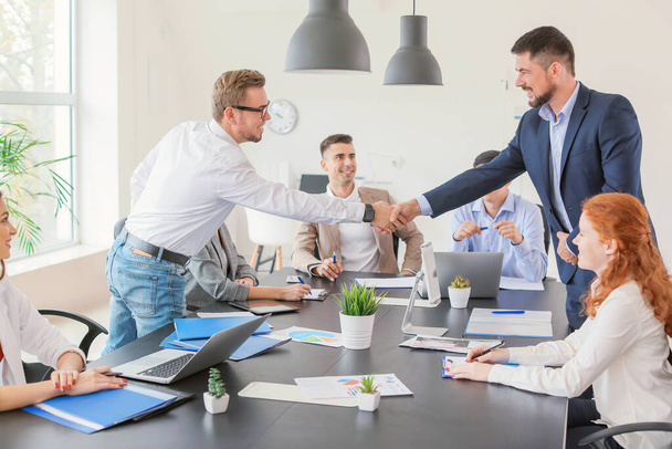 Young business people shaking hands during meeting in office - Photo, image
