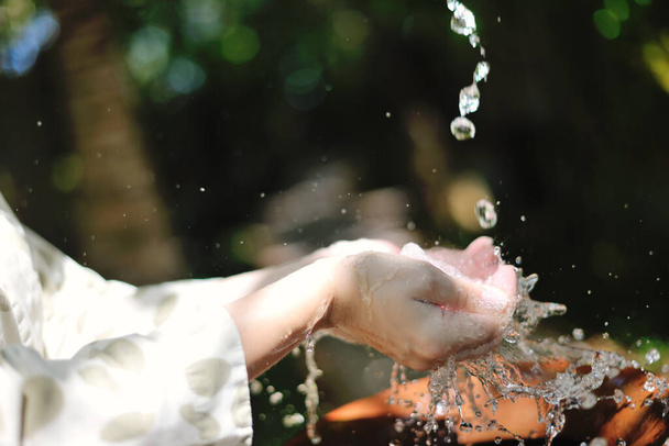 spritzende Frischwassertropfen auf weiche Hautpflege für sinnliche Frauenhände - Foto, Bild
