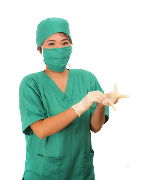 young beautiful and happy medicine doctor or chief hospital nurse in green scrubs and surgey hat and mask wearing protective latex gloves - Photo, Image