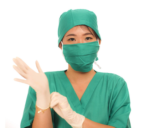 young beautiful and happy medicine doctor or chief hospital nurse in green scrubs and surgey hat and mask wearing protective latex gloves - Photo, Image