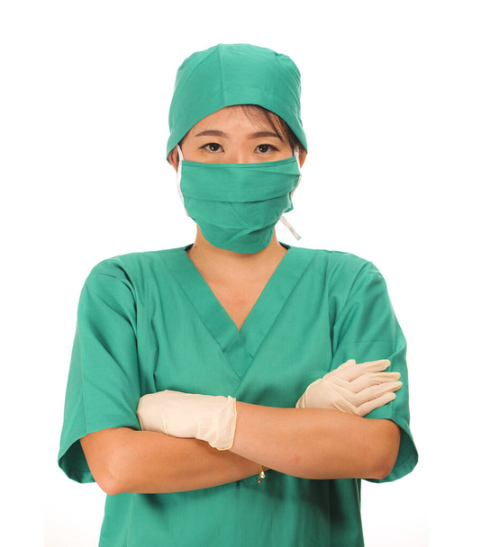 Genç, güzel ve mutlu doktor ya da yeşil önlüklü, ameliyat şapkalı ve maske takan koruyucu lateks eldivenli hastane başhemşiresi. - Fotoğraf, Görsel