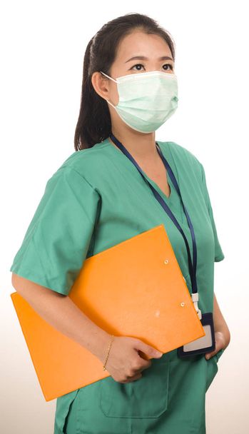 young beautiful Asian Korean medicine doctor woman or hospital nurse holding clipboard  in scrubs using protective medical face mask in prevention against virus infection isolated  - Zdjęcie, obraz