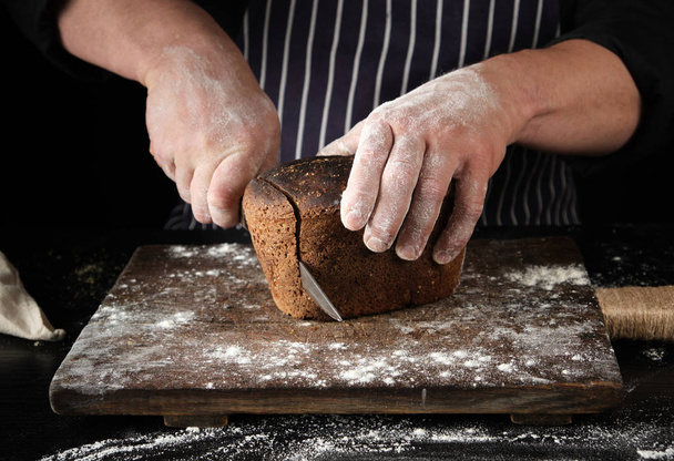 Šéfkuchař v černé uniformě má v ruce kuchyňský nůž a řezy - Fotografie, Obrázek