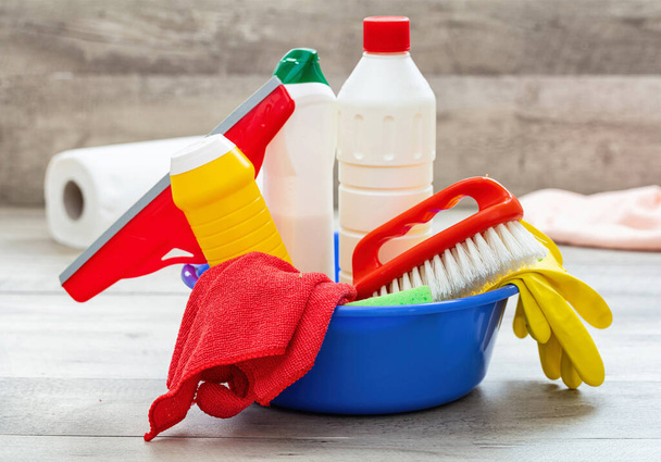 Cleaning supplies in a blue bowl, wooden floor background. - Foto, imagen