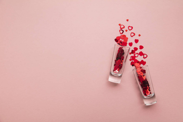 Valentines day shots. Shot glass with heart confetti on pastel pink background - Valokuva, kuva