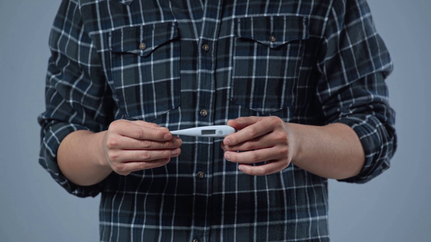 vista recortada del hombre que sostiene el termómetro electrónico aislado en gris
   - Metraje, vídeo