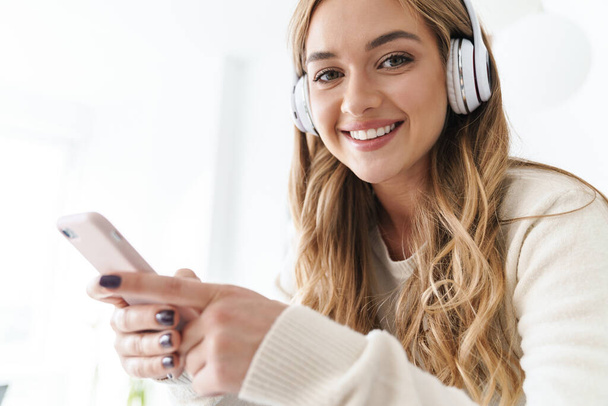 Photo of young smiling woman using headphones and cellphone - Φωτογραφία, εικόνα