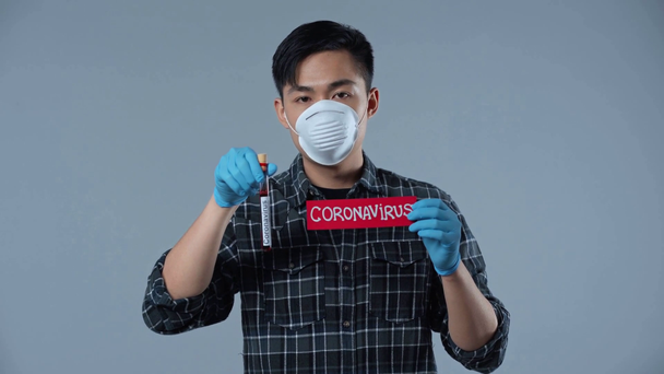 Aziatisch man met monster en papier met coronasvirus letters geïsoleerd op grijs  - Video