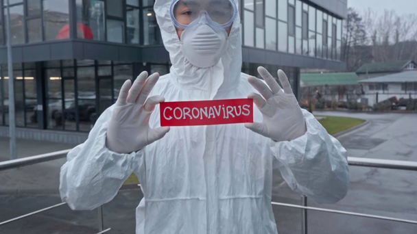 asian scientist holding paper with coronavirus lettering  - 映像、動画