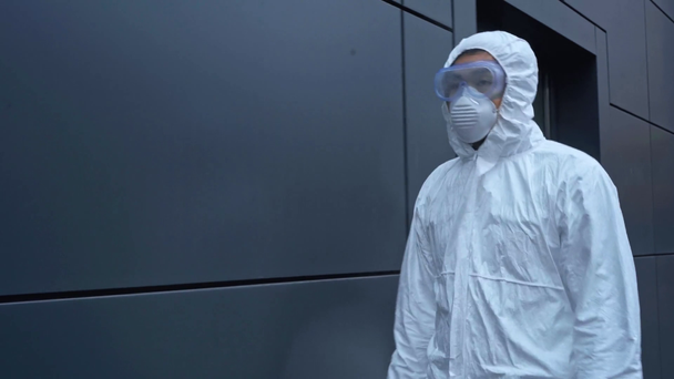 Asiatischer Wissenschaftler im Schutzanzug läuft in der Nähe von Gebäuden  - Filmmaterial, Video