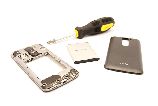 Rozmontowany smartfon z baterią i złotą osłoną na białym tle - Zdjęcie, obraz