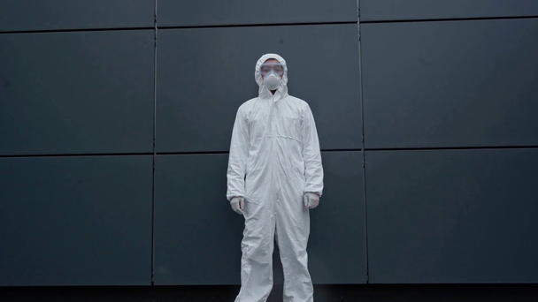 asijský vědec v ochranném obleku stojící v blízkosti budovy  - Záběry, video