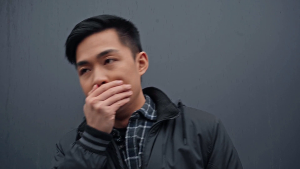 młody Azji człowiek kaszel na szary - Materiał filmowy, wideo