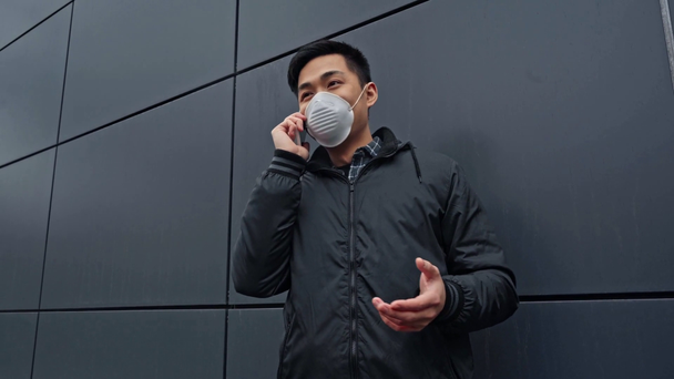 aziatische man in medisch masker praten op smartphone  - Video