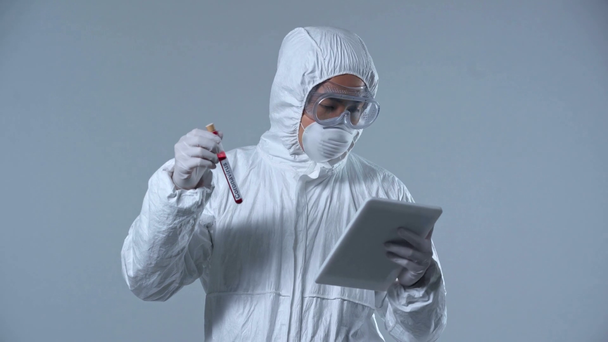азіатський вчений тримає цифровий планшет і зразок з коронавірусом, записуючи ізольовані на сірому
  - Кадри, відео