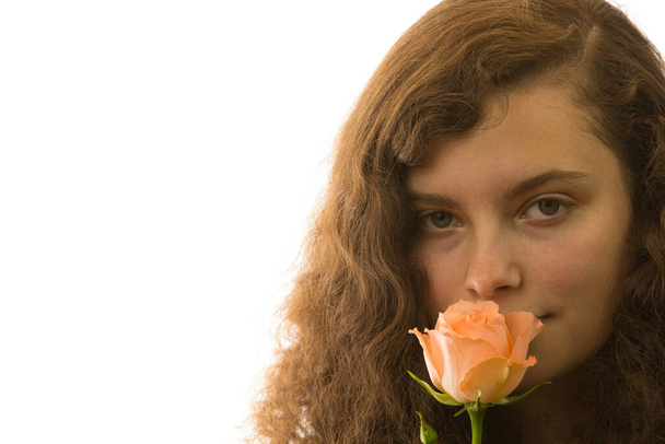 a young pretty woman holding a rose in her hand and smells it - Фото, зображення