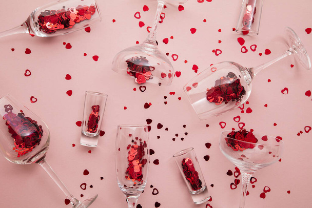 Valentines day date night background. Drinks glasses with red heart confetti. - Fotó, kép