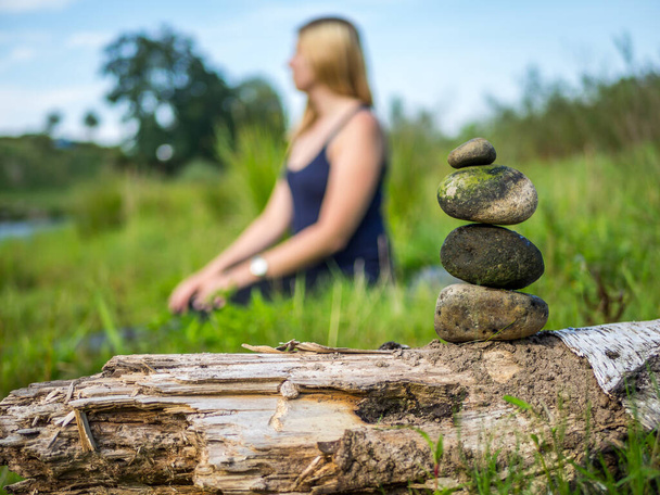 Γυναίκα κάθεται στη φύση και διαλογίζεται με πέτρες - Φωτογραφία, εικόνα