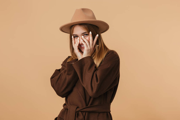 Image of young girl wearing hat smiling and covering her face wi - Photo, Image