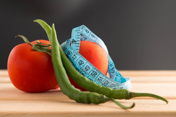 Hyödyllisiä vihanneksia keholle. Tomaatteja, paprikaa senttimetrillä ruumiin mittaamiseen. Urheilu, kunto, vitamiinit, terveellinen ruoka, vihannekset, ruokavalio, laihtumiseen, tomaatit, marjat, vihreä paprika
 - Valokuva, kuva