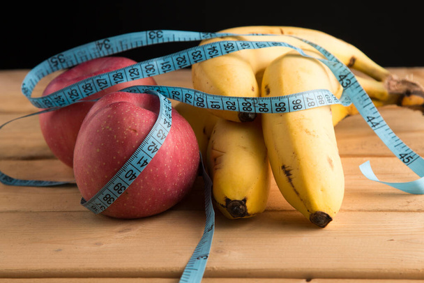 体に良い果物。リンゴ、バナナ、体を測定するセンチメートル。スポーツ、フィットネス、ビタミン、健康的な栄養、果物、リンゴ、バナナ、食事、痩身 - 写真・画像