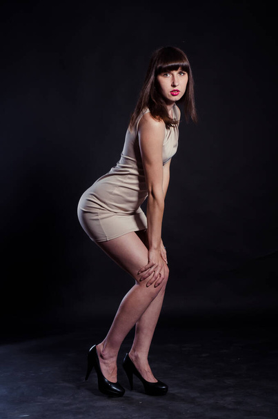 piękne brunetka dziewczyna w krótki beżowy strój pozowanie w studio  - Zdjęcie, obraz