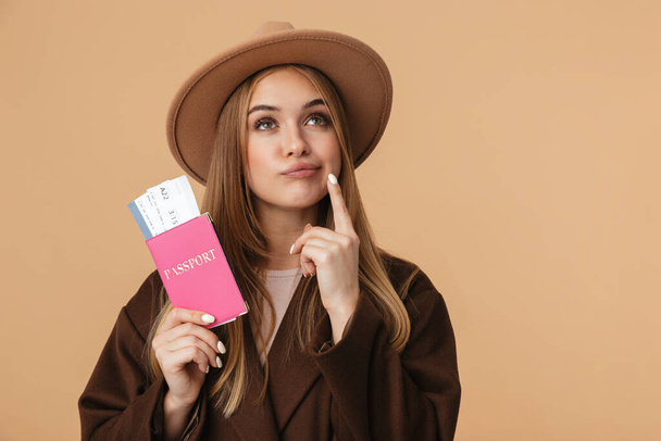 Image of optimistic girl wearing hat holding passport and travel - Foto, afbeelding