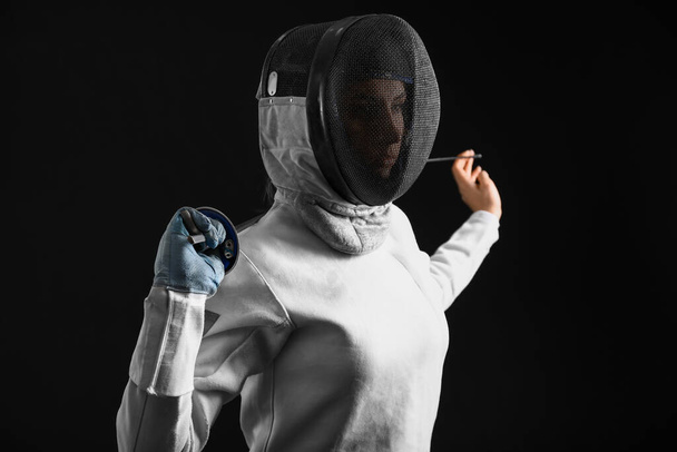 Young female fencer on dark background - Foto, afbeelding