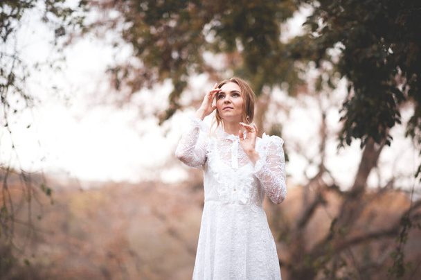 Krásná mladá dívka 20-24 let na sobě elegantní bílé šaty pózovat venku nad přírodou.  - Fotografie, Obrázek