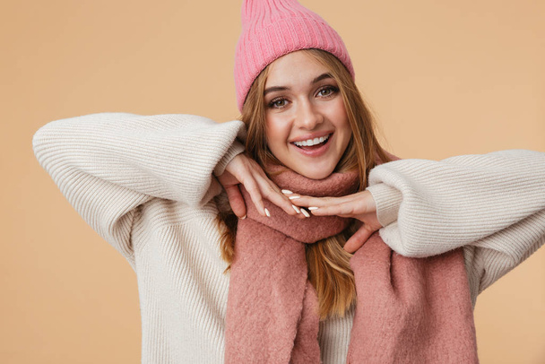 Image of girl in winter hat and scarf smiling and keeping hands  - Фото, изображение