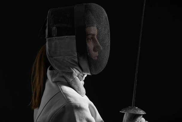Young female fencer on dark background - Foto, Bild