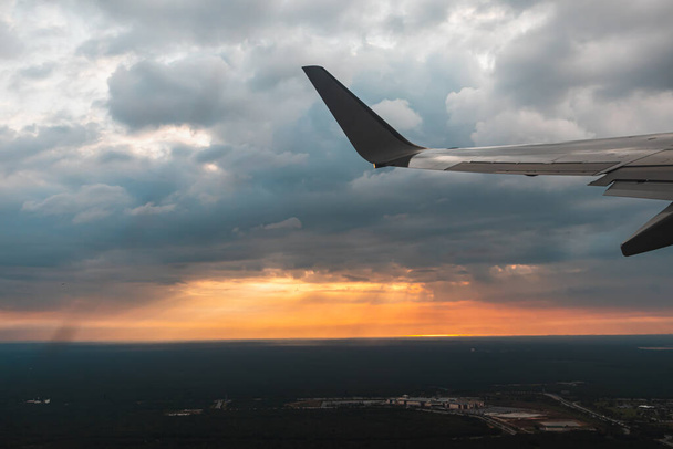 Flugzeug fliegt bei Sonnenuntergang über der Stadt. - Foto, Bild