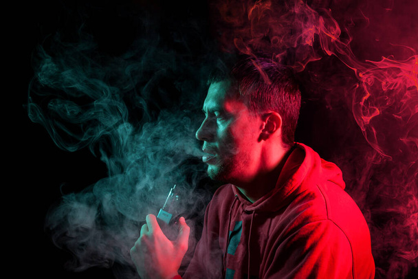 L'homme fume une cigarette électronique sur le fond sombre. Yo !
 - Photo, image