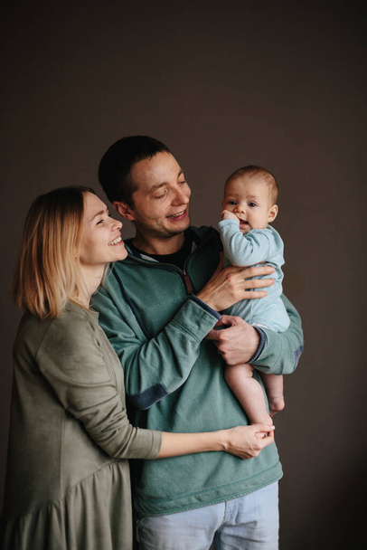 Portrait of a young happy family with the kid. Beautiful family hugs - Фото, изображение