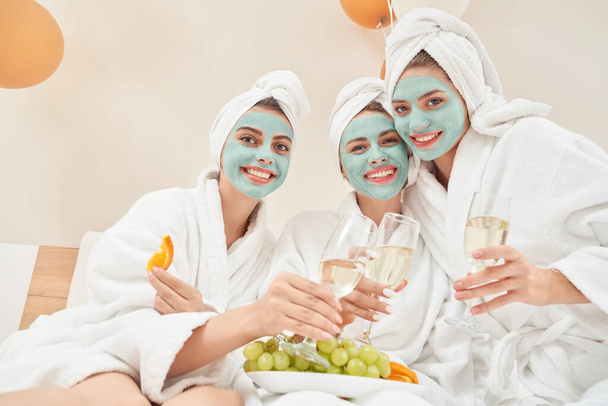 Female friends holdinng glasses of wine in bed. - Zdjęcie, obraz