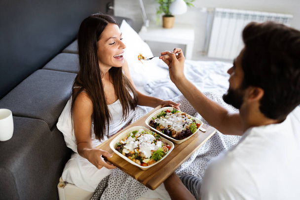 Care and romance at the morning. Happy young couple have breakfast at the bed - 写真・画像