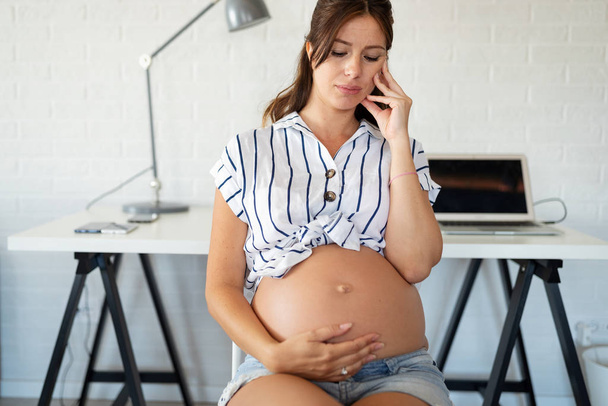 Young pregnant woman working from home. Career and pregnancy concept - Valokuva, kuva