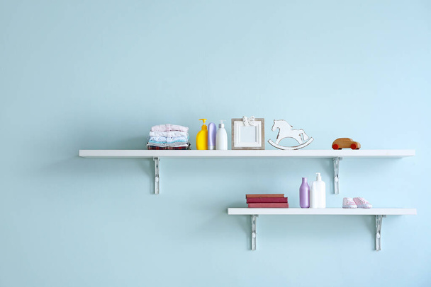 Shelves with baby accessories on color wall - Photo, Image