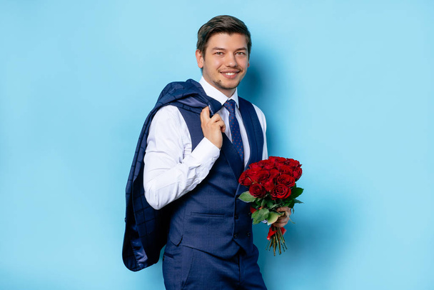 portrait of gentleman witn flowers isolated over blue background - Foto, imagen