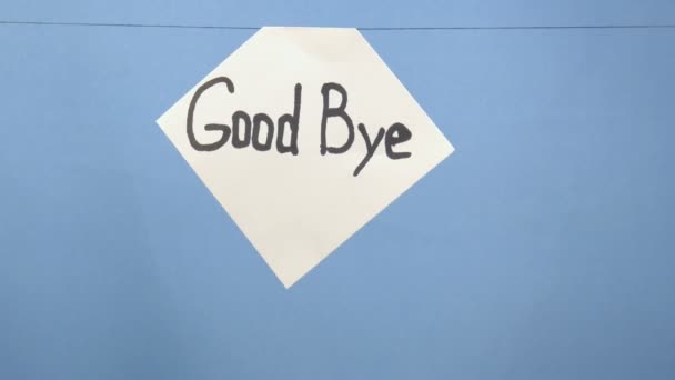 Queimando e fumando folha branca de papel com uma inscrição preta "adeus" em um fundo azul
 - Filmagem, Vídeo