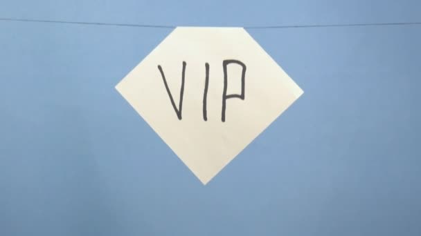 Κάψιμο και κάπνισμα λευκό φύλλο χαρτιού με μαύρη επιγραφή "vip" σε μπλε φόντο - Πλάνα, βίντεο