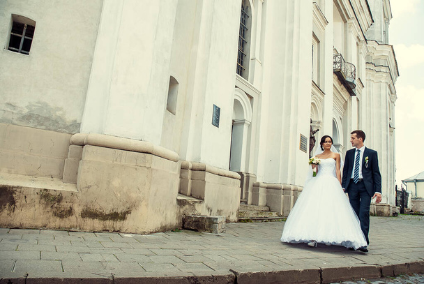 wide angle shot of bride and groom walking by old building - Foto, immagini
