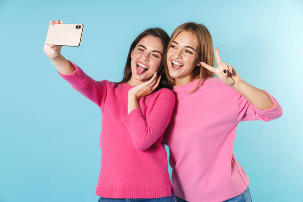 Photo of funny young women taking selfie and gesturing peace sign - 写真・画像