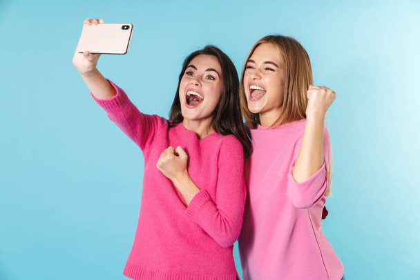 Photo of excited women taking selfie on cellphone with winners gesture - Foto, Bild